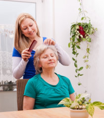 caregiver combing the hair of old woman