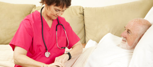 caregiver checking the pulse of old man